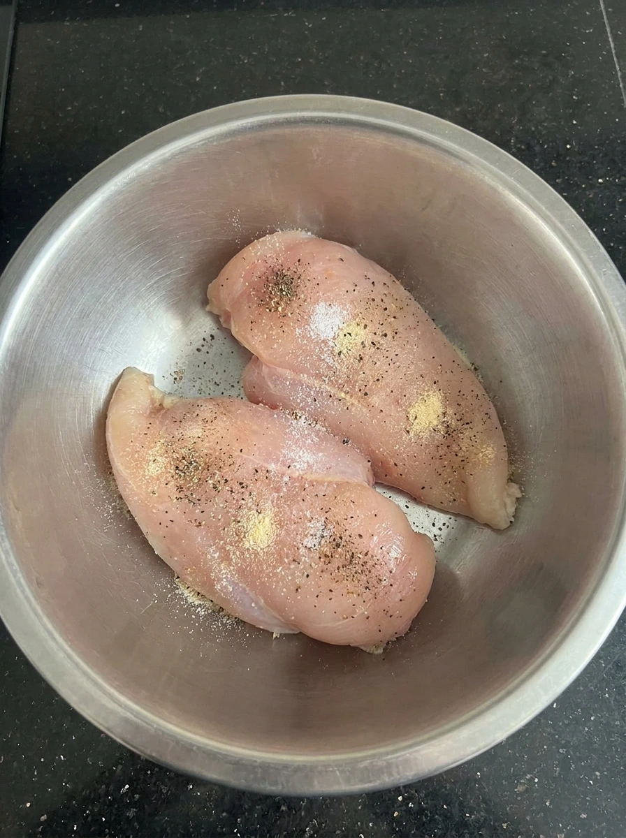 Two chicken breasts seasoned for Creamy Herb Chicken