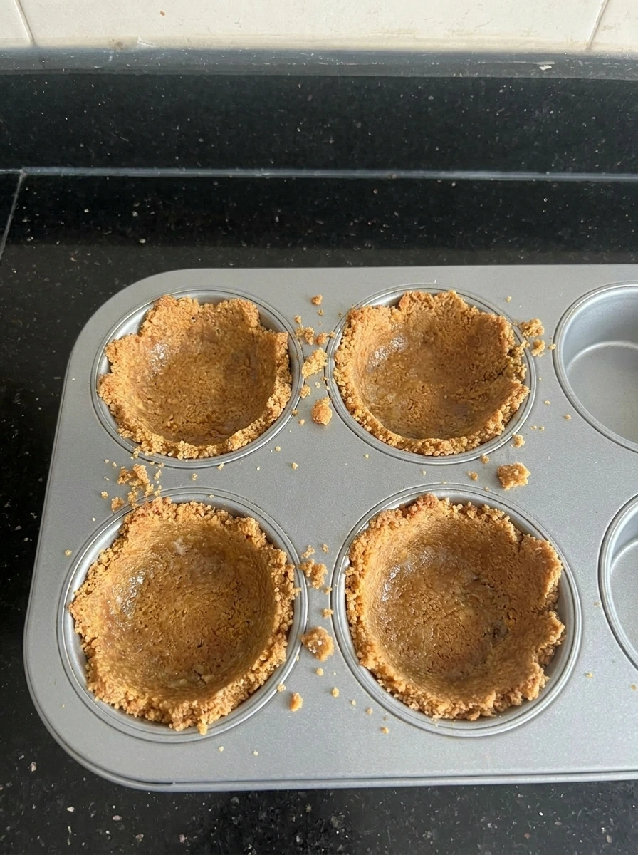 Mini cheesecake crust pressed into muffin cavities.