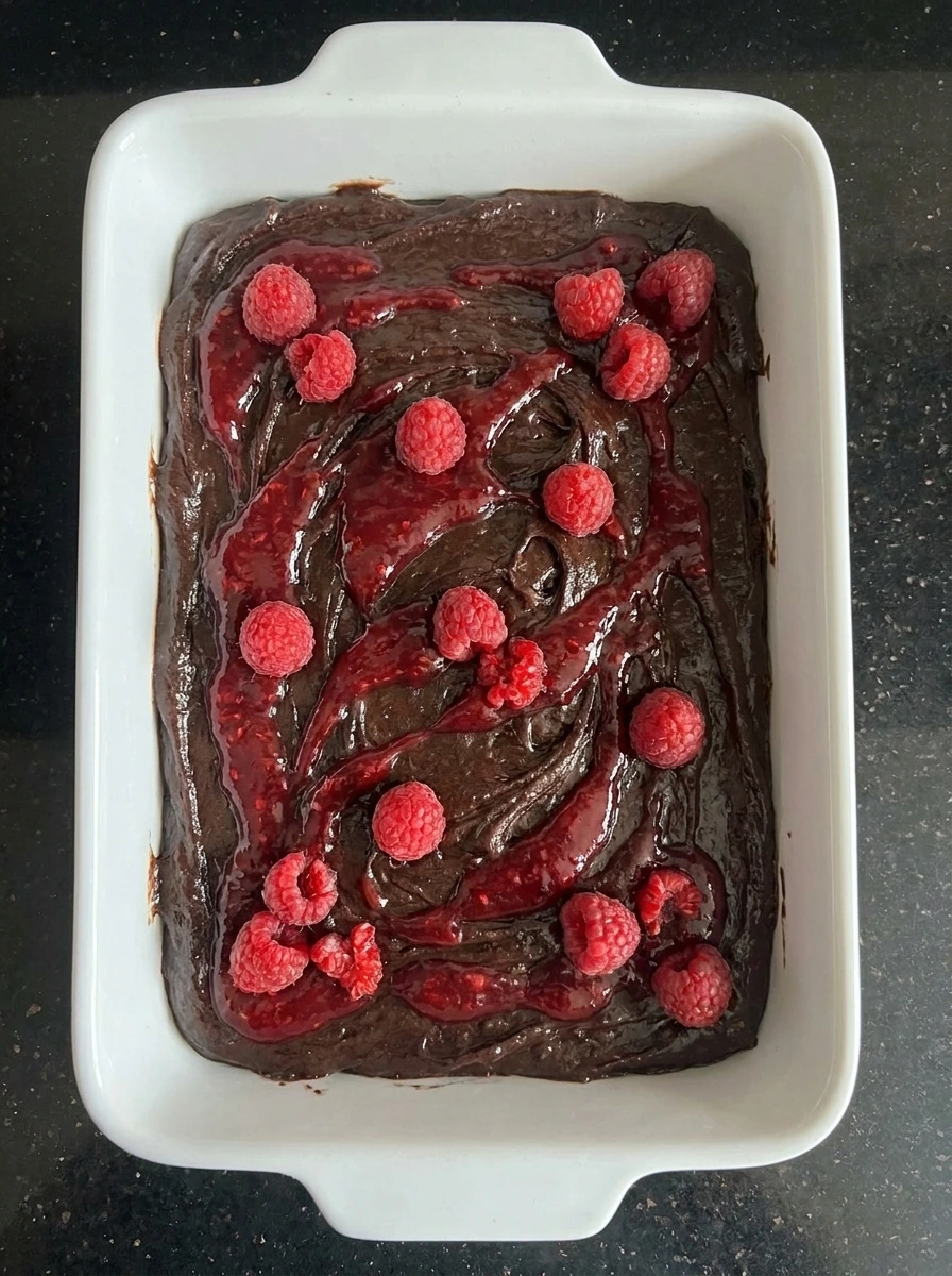 Brownie batter with raspberry swirls before baking