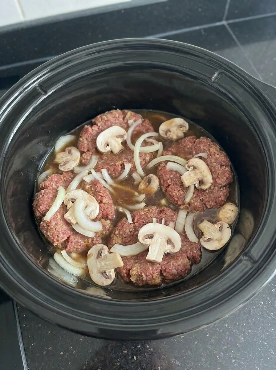 Salisbury steak patties layered with onions mushrooms and broth