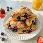 Golden Strawberry Blueberry Scones with juicy berries on white plate