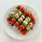 Caprese Skewers with cherry tomatoes and mozzarella and basil on a white plate