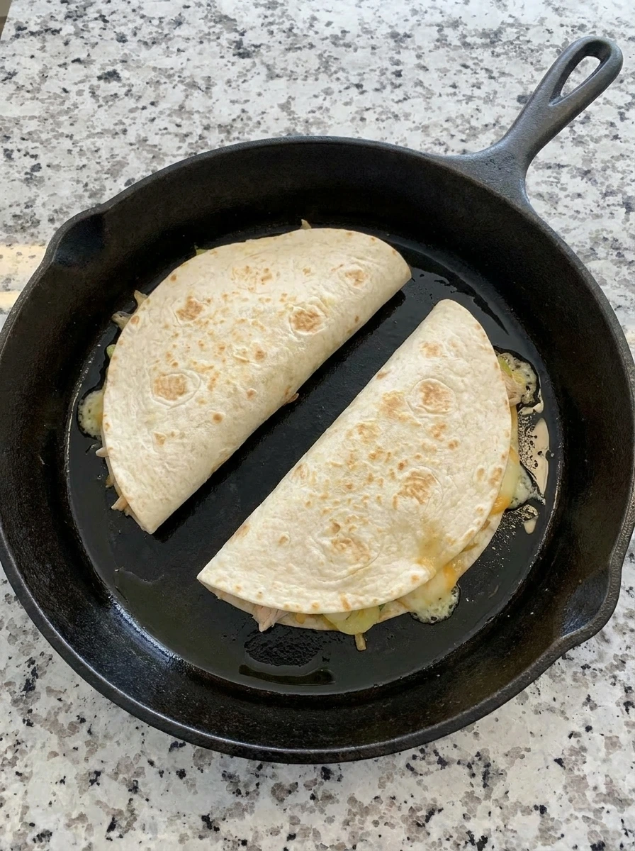 Folded banana pepper quesadillas browning in a skillet