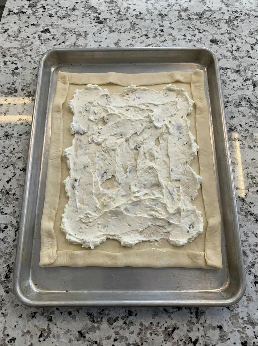 Cheese spread over puff pastry for Fig and Goat Cheese Tart