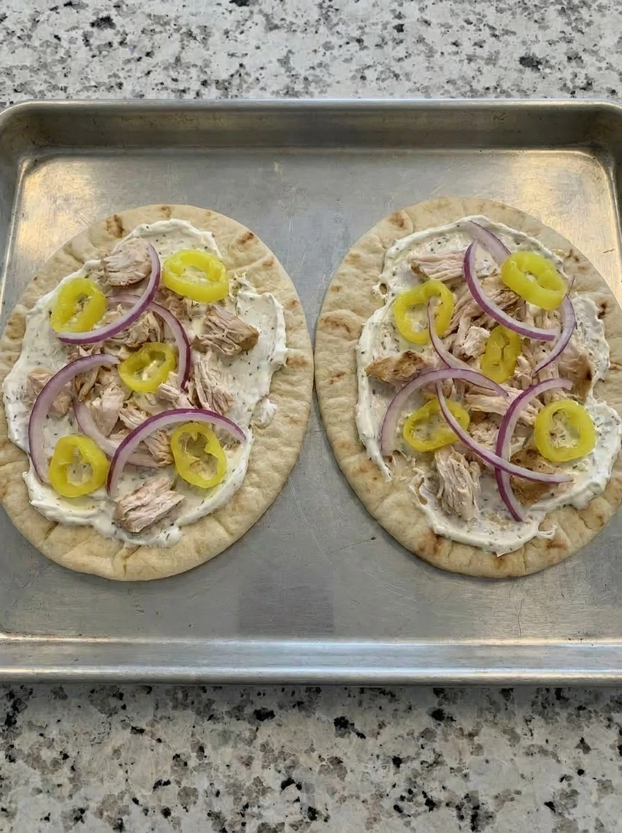 Chicken banana peppers and red onion scattered on Loaded Banana Pepper Flatbread