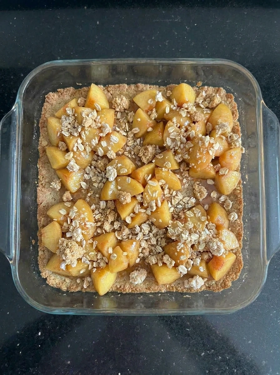 Crumble topping scattered over Peach Crumble Bars Everyone Loves