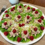 Raspberry Chicken Salad Lettuce Cups served on a white plate with raspberries and almonds