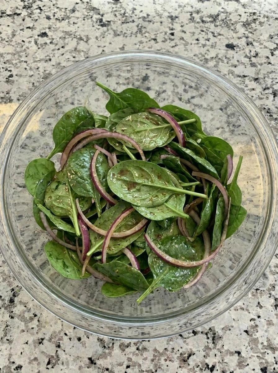 Spinach and red onion tossed with dressing for Raspberry Spinach Goat Cheese Salad