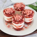 Strawberry Crunch Cheesecake Cups with creamy layers and pink cookie topping