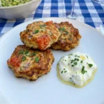 Golden Tomato Fritters on a white plate with yogurt dip