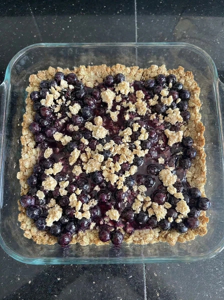 Crumble topping scattered over huckleberry filling