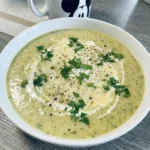 Creamy Zucchini Soup with Parmesan in a white bowl with melted cheese and parsley