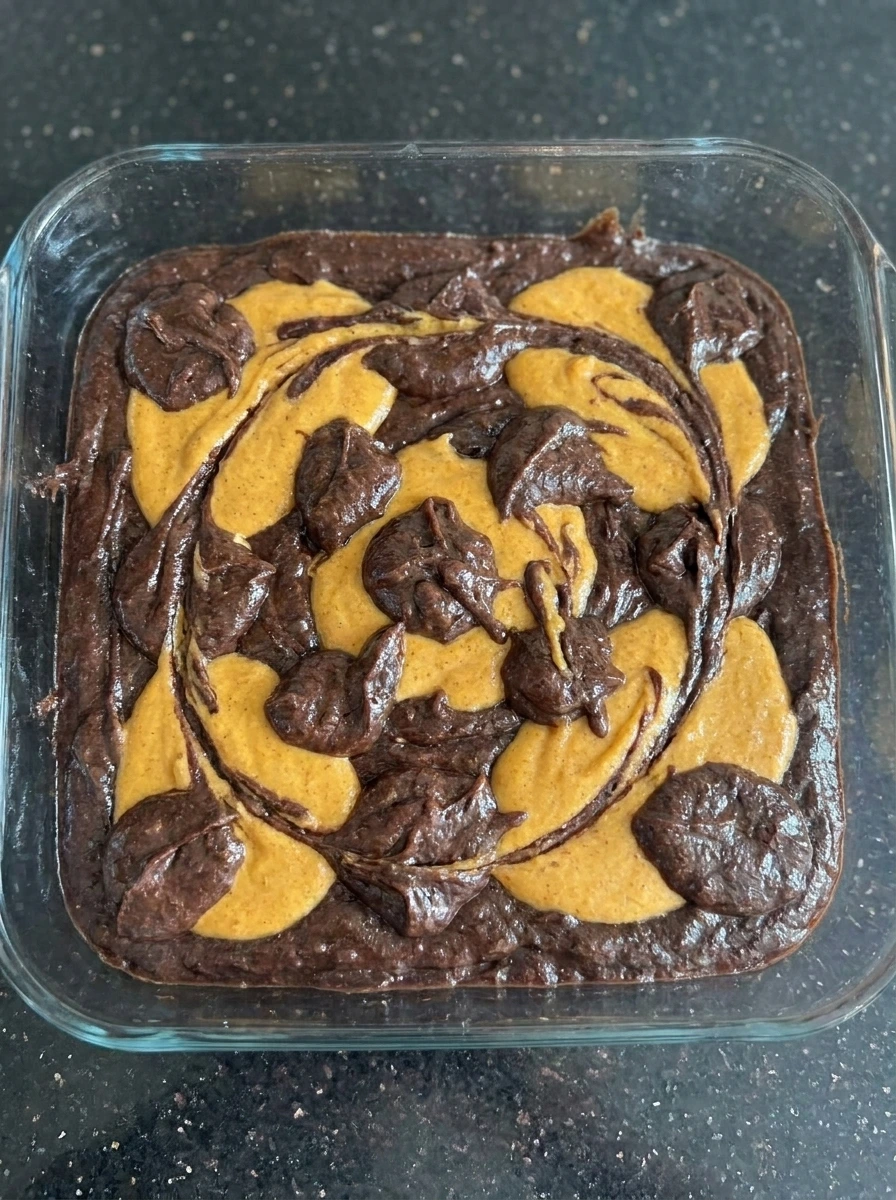 Pumpkin cheesecake swirl dragged through brownie batter
