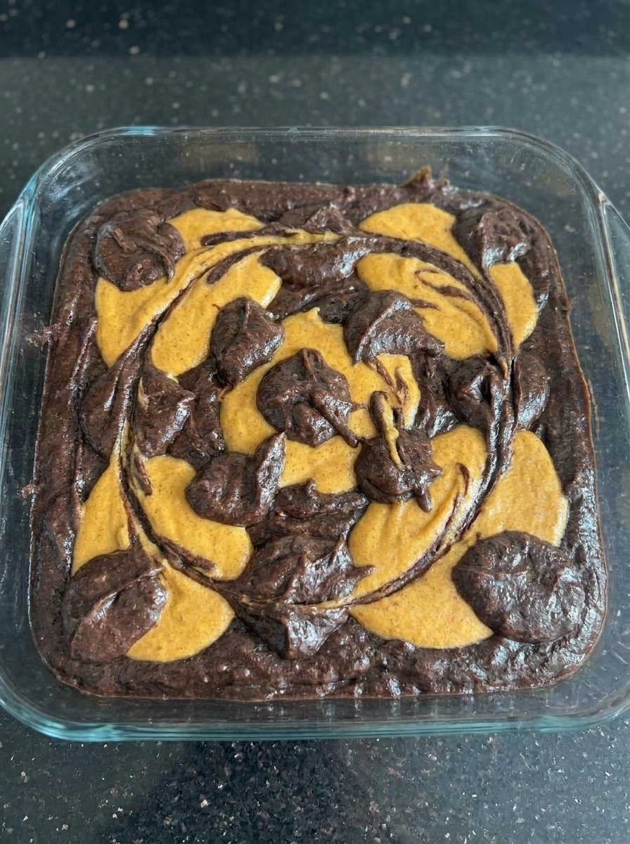 Baked Pumpkin Cheesecake Brownies with cracked tops and browned edges
