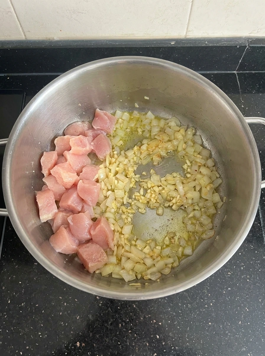 Cut chicken with softened onion and garlic for Chicken Cordon Bleu Soup
